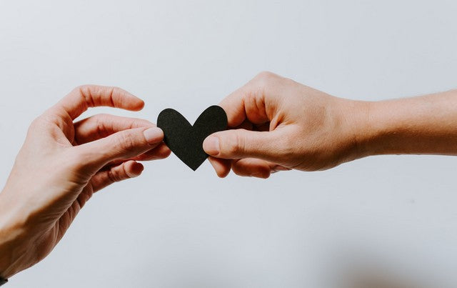 pareja compartiendo un recorte de un corazón entre ellos