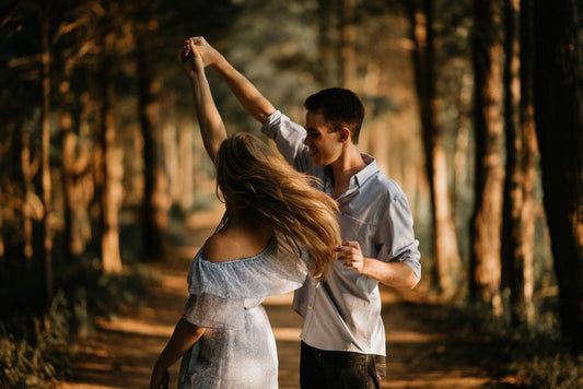 pareja bailando en un bosque hermoso con luz infiltrandose entre árboles