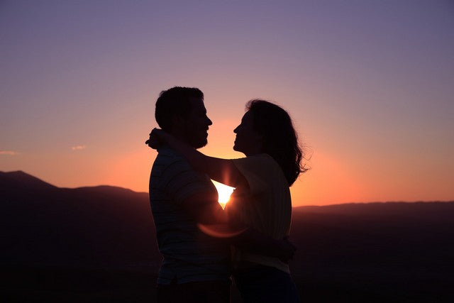 pareja abrazandose con atardecer de fondo