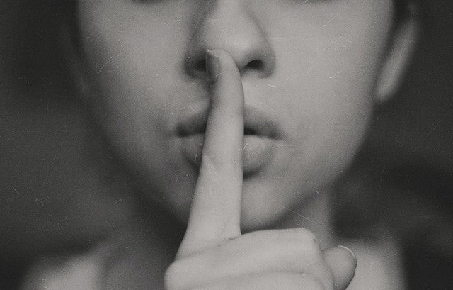 mujer haciendo señal de mantener secreto