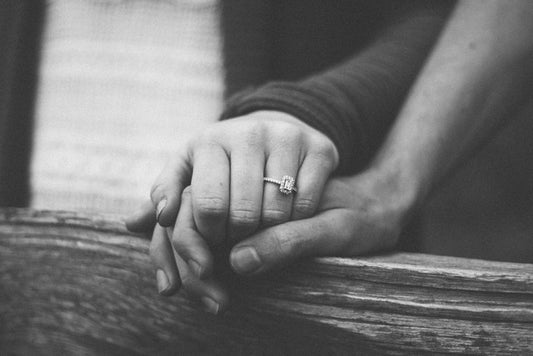foto en blanco y negro de manos de una pareja casada sobre una baranda de madera