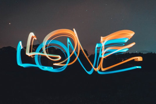 love escrito con luces de neon azul y naranja con un fondo del horizonte en la noche
