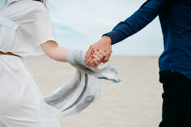 pareja tomados de la mano con un el vestido de ella envolviendo las manos