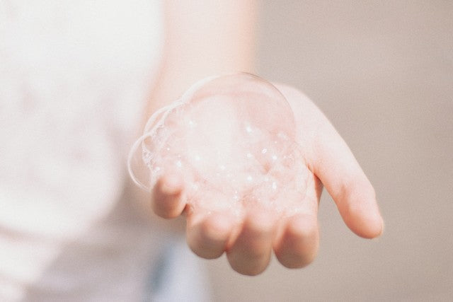mano con una burbuja de jabón grande rodeadas de burbujas más pequeñas