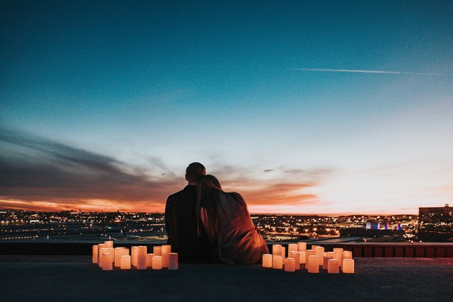 pareja sentada uno al lado del otro en techo mirando el cielo